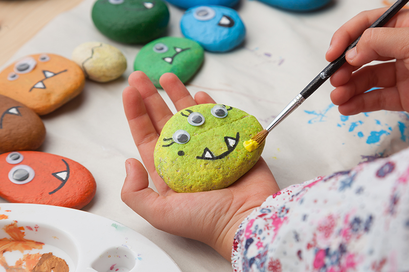 Child painting a stone monster craft By ISO101 adobe stock