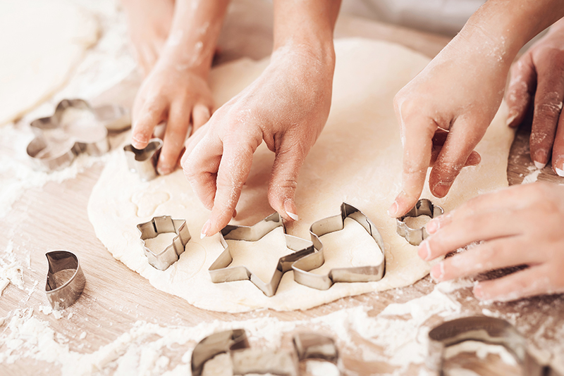 Female and children's hands make form for biscuits with help of baking moulds. By freeograph on adobe stock
