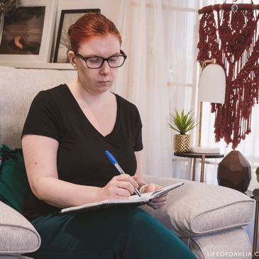 A woman sitting on a couch while writing in a notebook