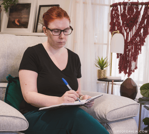 A woman sitting on a couch while writing in a notebook