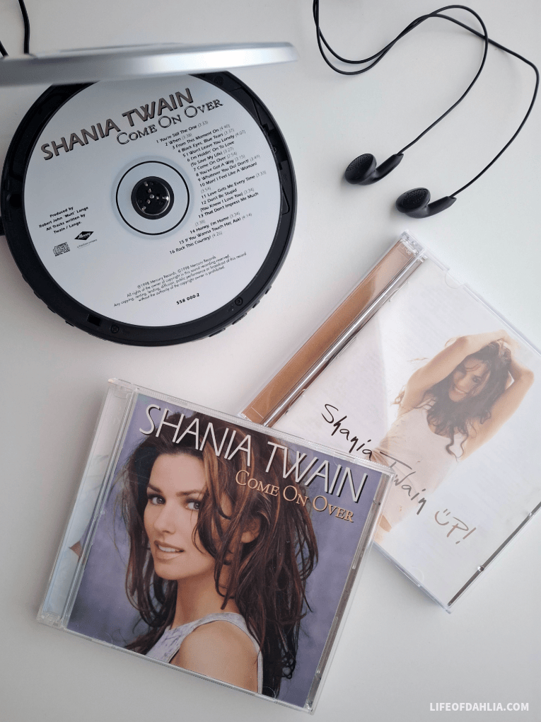 A portable cd player with Shania Twain's 'Come on over' cd inside. below is the cd covers for 'Come on over' and 'Up!'