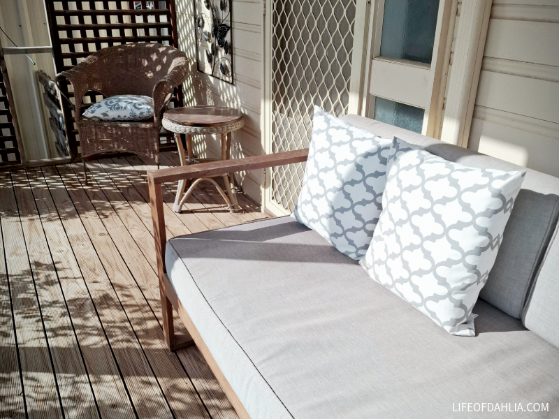 an outdoor couch and chair on a porch